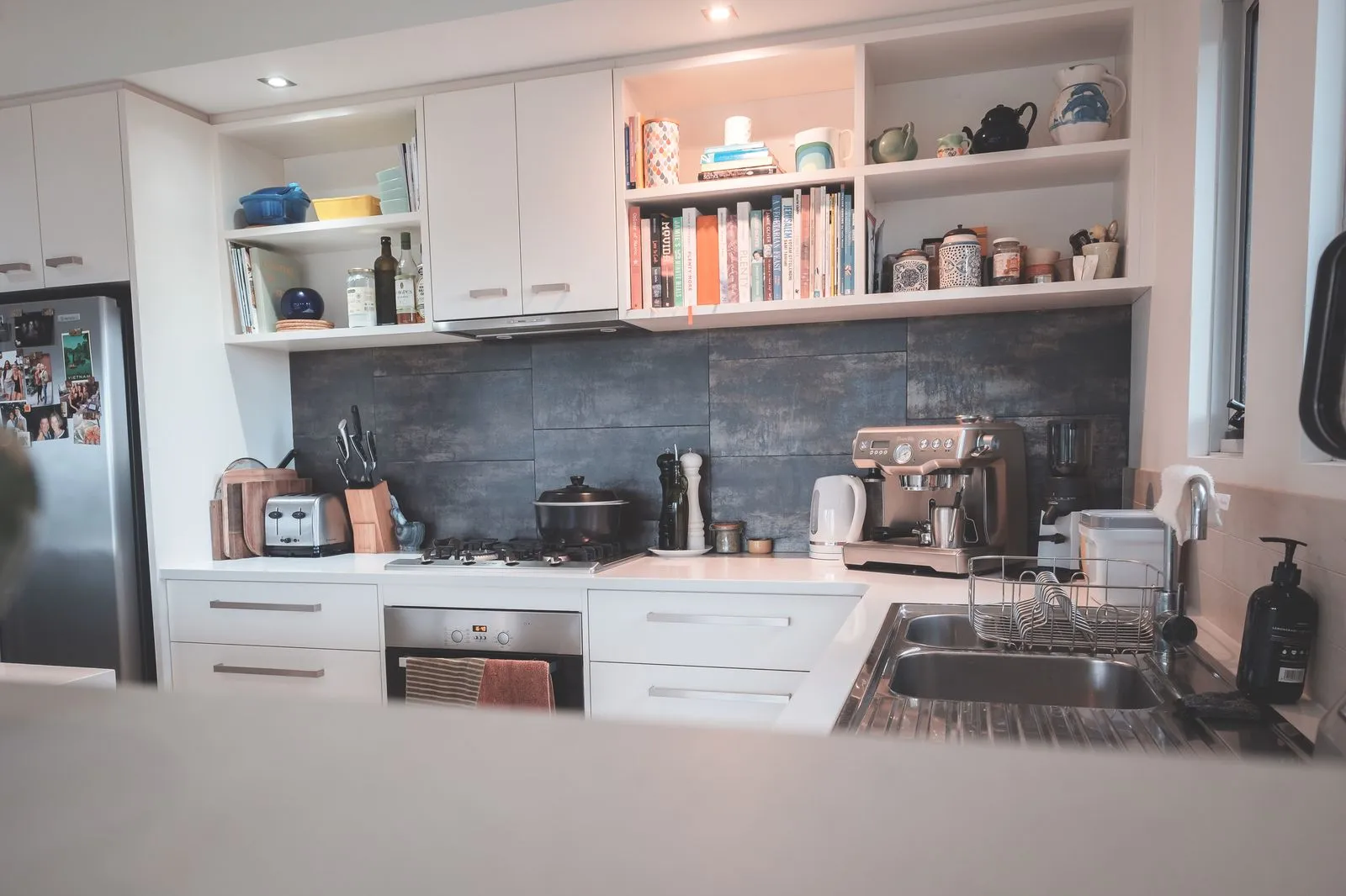 Kuzhinë kompakte apartamenti me fronte të bardha dhe suvatim të errët